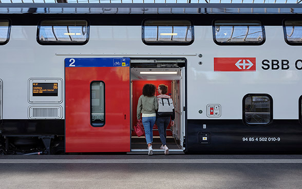 Zwei Passagiere besteigen einen Zug der SBB.